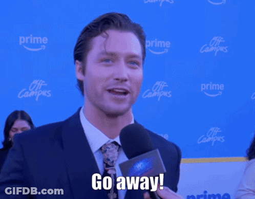 A Man In A Suit And Tie Is Holding A Microphone And Saying Go Away GIF