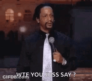A Man In A Suit And Tie Is Holding A Microphone And Saying Wtf You Juss Say ? . GIF