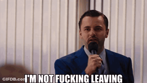 A Man In A Suit And Tie Is Holding A Microphone And Says I 'M Not Fucking Leaving GIF