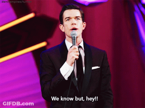 A Man In A Suit And Tie Is Holding A Microphone And Says We Know But Hey GIF