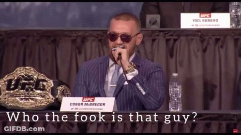 A Man In A Suit And Tie Is Holding A Microphone In Front Of A Sign That Says Ufc GIF