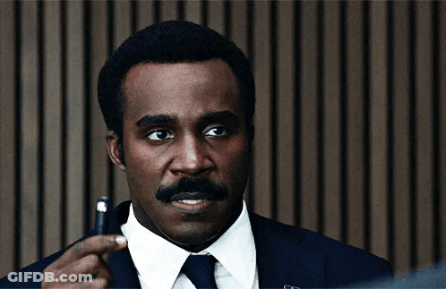 A Man In A Suit And Tie Is Holding A Pen GIF