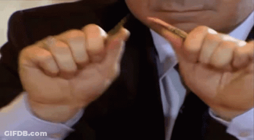 A Man In A Suit And Tie Is Holding A Pen Between His Fingers . GIF