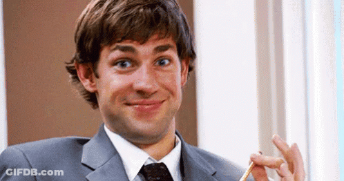 A Man In A Suit And Tie Is Holding A Pencil In His Hand And Smiling . GIF