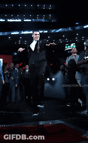 A Man In A Suit And Tie Is Holding A Piece Of Paper GIF