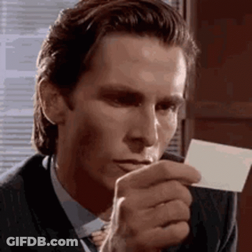 A Man In A Suit And Tie Is Holding A Piece Of Paper In Front Of His Mouth . GIF
