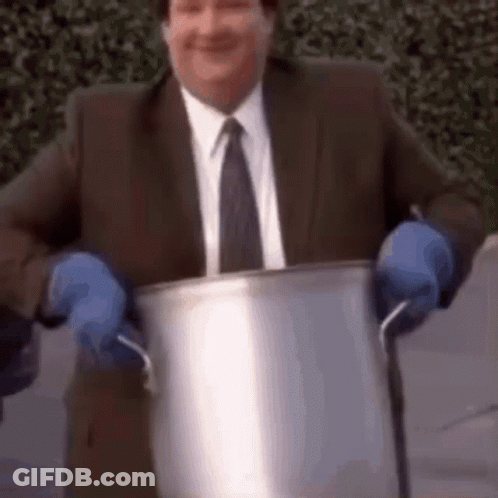 A Man In A Suit And Tie Is Holding A Pot With Blue Gloves On . GIF
