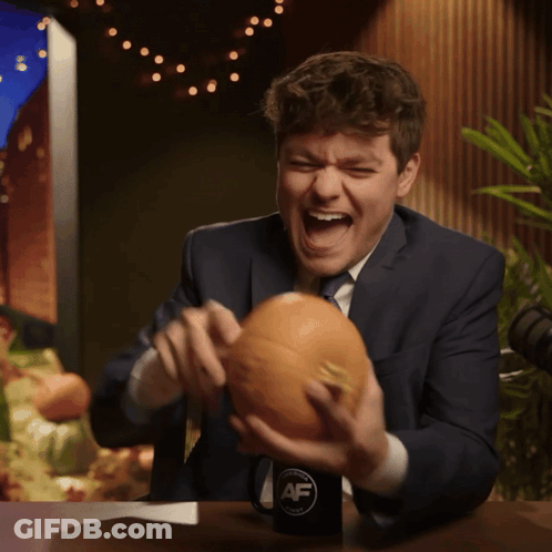 A Man In A Suit And Tie Is Holding A Pumpkin In Front Of A Cup That Says Af GIF