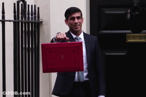 A Man In A Suit And Tie Is Holding A Red Briefcase That Says ' British ' On It GIF