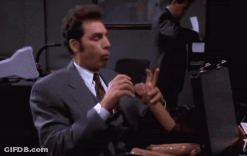 A Man In A Suit And Tie Is Holding A Sausage GIF