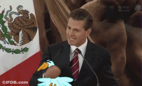 A Man In A Suit And Tie Is Holding A Stuffed Penguin In Front Of A Microphone . GIF