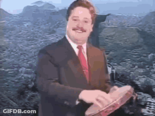A Man In A Suit And Tie Is Holding A Tambourine In His Hands GIF