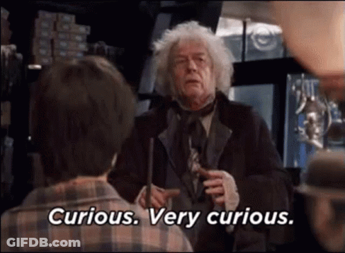 A Man In A Suit And Tie Is Holding A Wand And Talking To A Boy . GIF