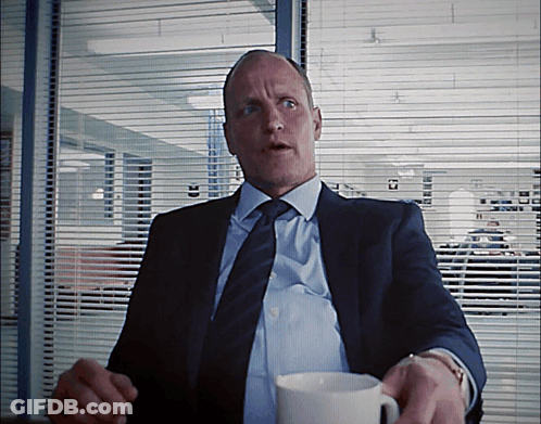A Man In A Suit And Tie Is Holding A White Cup GIF
