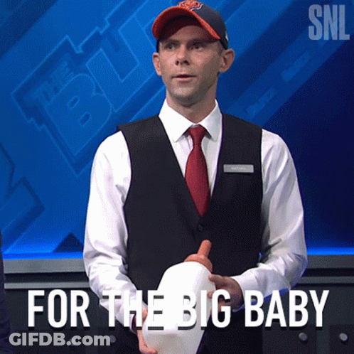 A Man In A Suit And Tie Is Holding A White Hat With The Words For The Big Baby Written Below Him GIF