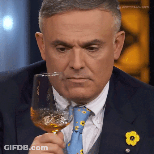 A Man In A Suit And Tie Is Holding A Wine Glass GIF