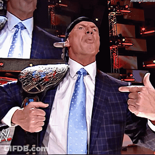 A Man In A Suit And Tie Is Holding A Wrestling Championship Belt Around His Shoulder GIF