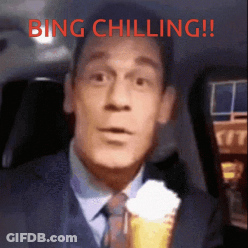 A Man In A Suit And Tie Is Holding An Ice Cream Cone With Whipped Cream And The Words Bing Chilling Above Him GIF