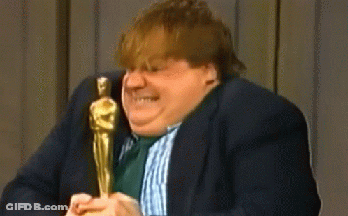A Man In A Suit And Tie Is Holding An Oscar Statue And Talking Into A Microphone . GIF