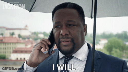 A Man In A Suit And Tie Is Holding An Umbrella And Talking On A Cell Phone With The Words I Will Below Him GIF