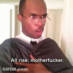 A Man In A Suit And Tie Is Holding His Chest And Says All Rise Motherfucker GIF