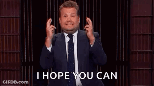 A Man In A Suit And Tie Is Holding His Fingers Crossed While Giving A Speech . GIF