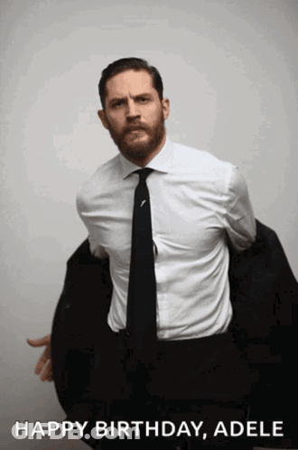 A Man In A Suit And Tie Is Holding His Jacket Over His Shoulder And Says " Happy Birthday Adele " GIF