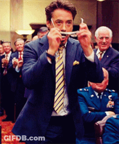 A Man In A Suit And Tie Is Holding Something In His Hand GIF