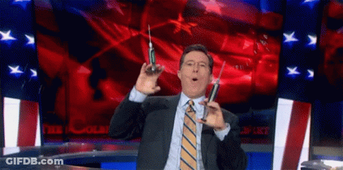 A Man In A Suit And Tie Is Holding Two Syringes In His Hands . GIF
