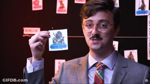 A Man In A Suit And Tie Is Holding Up A Sticker That Says Kotal Karim GIF
