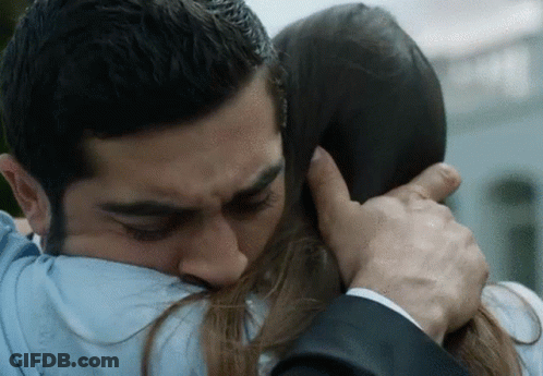 A Man In A Suit And Tie Is Hugging A Woman In A Blue Shirt GIF