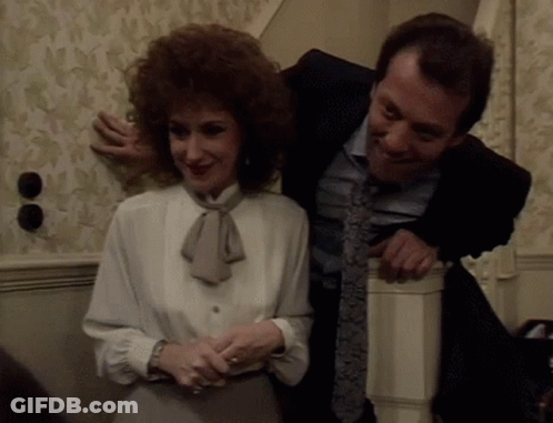 A Man In A Suit And Tie Is Hugging A Woman In A White Blouse GIF