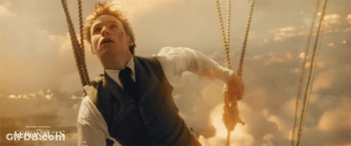 A Man In A Suit And Tie Is In A Hot Air Balloon With The Words Aeronauts On The Bottom GIF