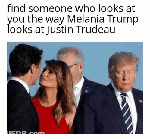 A Man In A Suit And Tie Is Kissing A Woman On The Cheek . GIF