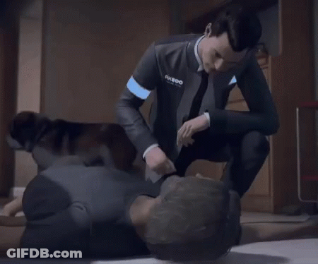A Man In A Suit And Tie Is Kneeling Down Next To Another Man Laying On The Floor . GIF