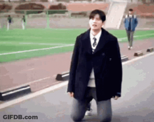 A Man In A Suit And Tie Is Kneeling Down On The Ground . GIF
