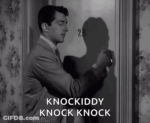 A Man In A Suit And Tie Is Knocking On A Door That Says 2B On It GIF