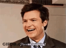 A Man In A Suit And Tie Is Laughing . GIF