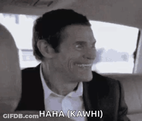 A Man In A Suit And Tie Is Laughing In A Car . GIF