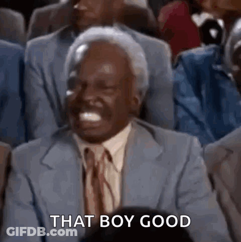 A Man In A Suit And Tie Is Laughing In A Crowd Of People . GIF