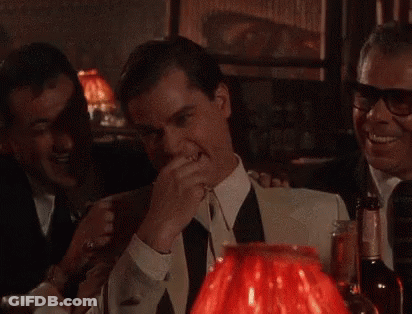 A Man In A Suit And Tie Is Laughing In Front Of A Red Lamp .. GIF