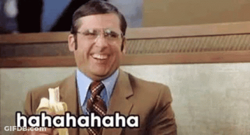 A Man In A Suit And Tie Is Laughing While Holding A Banana . GIF