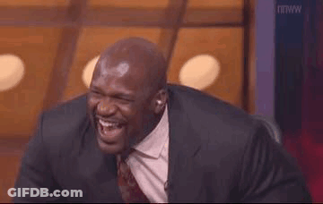 A Man In A Suit And Tie Is Laughing While Sitting In A Chair . GIF