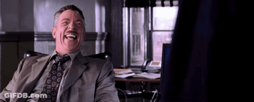 A Man In A Suit And Tie Is Laughing While Sitting In Front Of A Computer . GIF