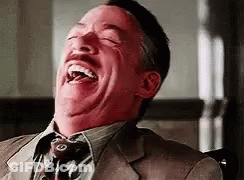 A Man In A Suit And Tie Is Laughing With His Eyes Closed And His Mouth Open . GIF