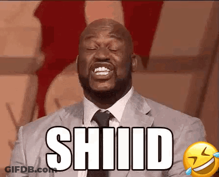 A Man In A Suit And Tie Is Laughing With His Eyes Closed And The Word Shiiid On His Face . GIF