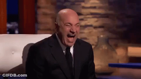 A Man In A Suit And Tie Is Laughing With His Mouth Open . GIF