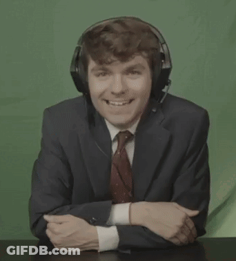 A Man In A Suit And Tie Is Laughing With His Mouth Open While Wearing Headphones . GIF