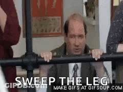 A Man In A Suit And Tie Is Leaning On A Railing And Says `` Sweep The Leg '' . GIF