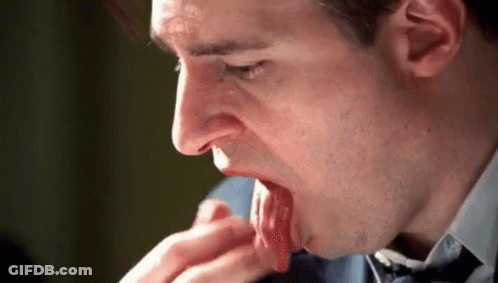 A Man In A Suit And Tie Is Licking His Hand . GIF